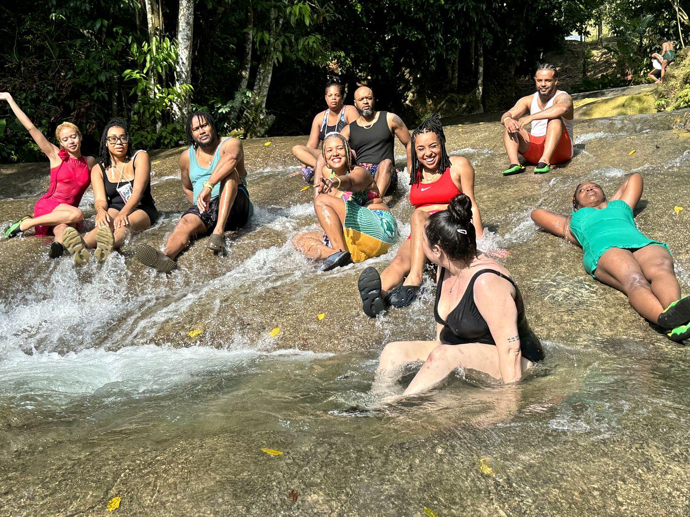 Guests sliding and laughing down a sunlit river cascade