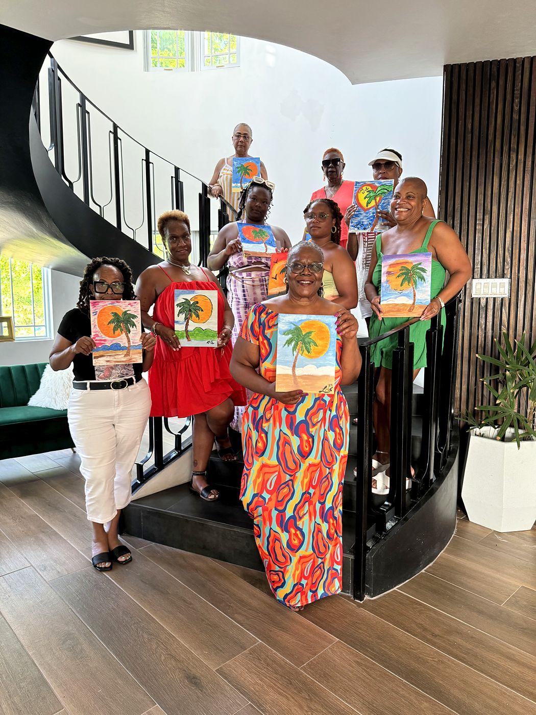 Women on the villa’s spiral staircase holding their palm tree paintings