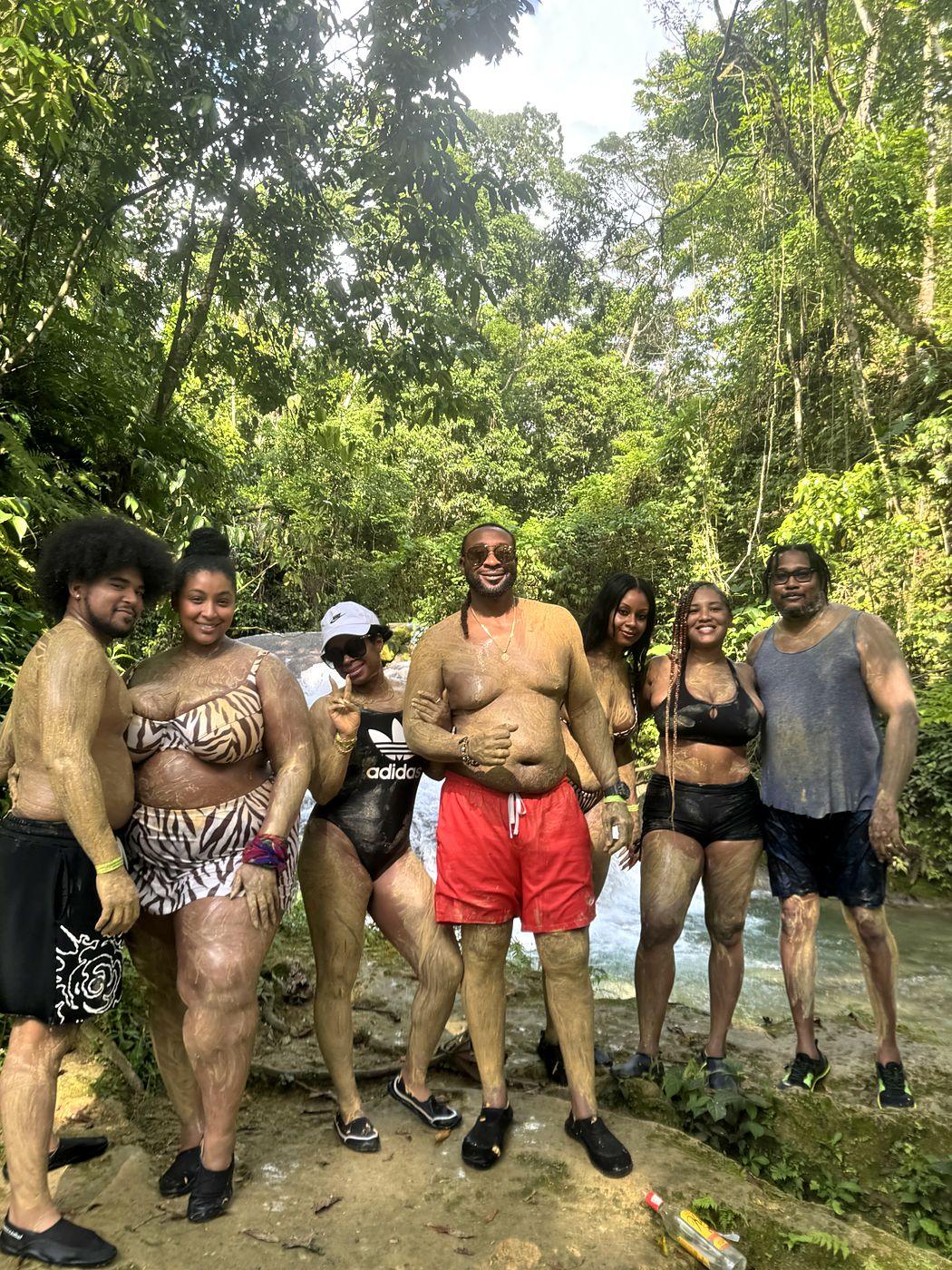 Guests covered in river clay standing by a waterfall
