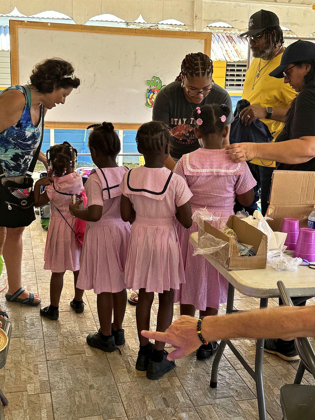 Volunteers with young schoolgirls in pink gingham uniforms