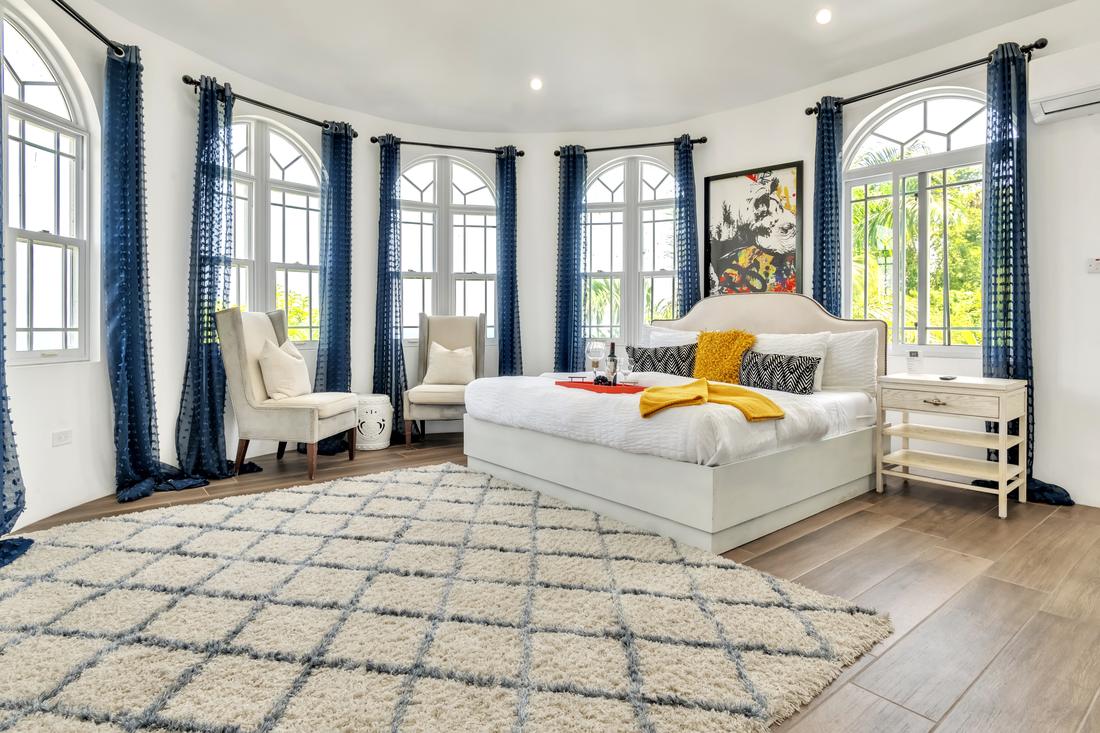 A round bedroom ringed with arched windows and navy curtains