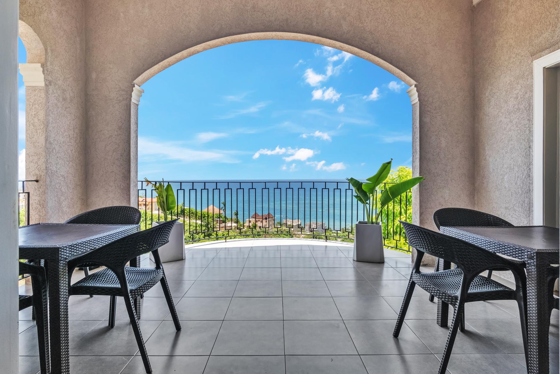 An arched balcony at the villa opening onto the blue Caribbean Sea